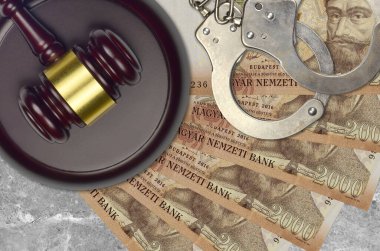 2000 Macar forint banknotları ve mahkeme masasında polis kelepçeli yargıç çekici. Yargılama ya da rüşvet kavramı. Vergi kaçırma ya da vergi kaçırma
