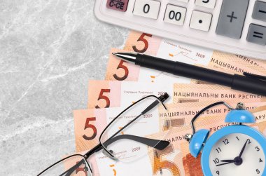 5 Belorus rublesi banknot, hesap makinesi ve gözlük ve kalem. İş kredisi ya da vergi ödeme sezonu kavramı. Mali planlama ve vergi ödeme zamanı