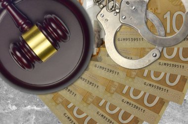 100 Kanada doları banknotlar ve mahkeme masasında polis kelepçeli yargıç çekici. Yargılama ya da rüşvet kavramı. Vergi kaçırma ya da vergi kaçırma