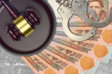 100 Ukrayna hrivniası faturası ve mahkeme masasında polis kelepçeleri olan yargıç çekici. Yargılama ya da rüşvet kavramı. Vergi kaçırma ya da vergi kaçırma