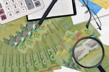 20 Kanada doları banknot ve gözlüklü ve kalemli hesap makinesi. Vergi ödeme sezonu kavramı veya yatırım çözümleri. Yüksek maaşlı bir iş arıyorum.
