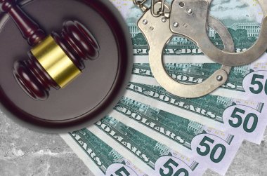 50 dolarlık banknotlar ve mahkeme masasında polis kelepçeli yargıç çekici. Yargılama ya da rüşvet kavramı. Vergi kaçırma ya da vergi kaçırma