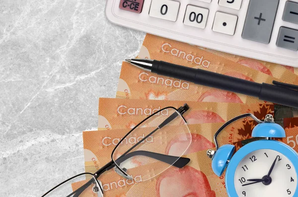 50 Canadian dollars bills and calculator with glasses and pen. Business loan or tax payment season concept. Financial planning and time to pay taxes