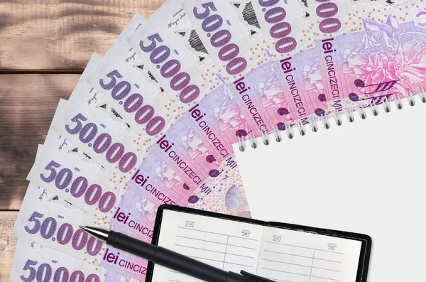 50000 Romanian leu bills fan and notepad with contact book and black pen. Concept of financial planning and business strategy. Accounting and investment