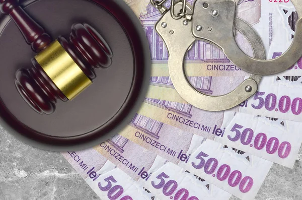50000 Romanian leu bills and judge hammer with police handcuffs on court desk. Concept of judicial trial or bribery. Tax avoidance or tax evasion