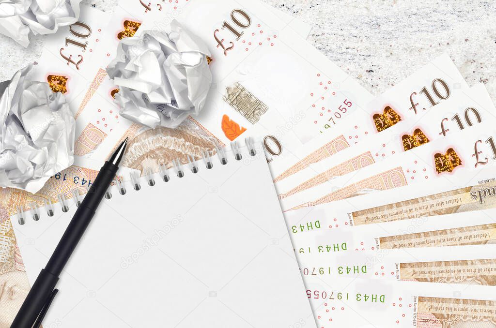 10 British pounds bills and balls of crumpled paper with notepad. Bad ideas or less of inspiration concept. Searching ideas for investment