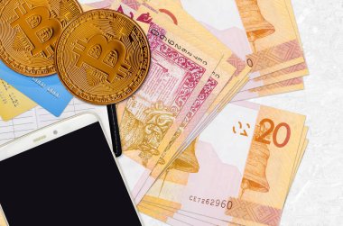 20 Belorus rublesi banknotları ve akıllı telefon ve kredi kartlarıyla altın bitcoin. Kripto para birimi yatırım konsepti. Kripto madenciliği veya ticari işlemler