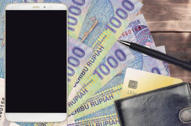 1000 Endonezya rupia banknotu ve çantalı ve kredi kartlı akıllı telefon. E-ödemeler ya da e-ticaret konsepti. Taşınabilir aygıt kullanımı ile çevrimiçi alışveriş ve iş