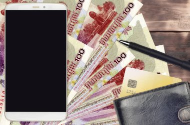 100 Kamboçyalı isyan faturası ve çantalı ve kredi kartlı akıllı telefon. E-ödemeler ya da e-ticaret konsepti. Taşınabilir aygıt kullanımı ile çevrimiçi alışveriş ve iş