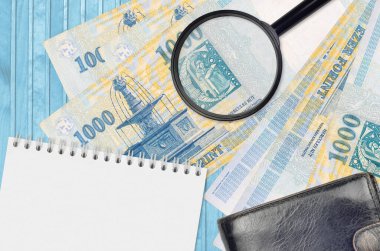 1000 Macar forint banknotu ve siyah çantalı ve not defterli büyüteç. Sahte para konsepti. Sahte parayı tespit etmek için para banknotlarındaki farklılıkları araştır