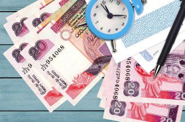 20 Sri Lanka rupisi ve içinde kalem ve zarflar olan çalar saat. Vergi sezonu konsepti, kredi veya kredi için ödeme tarihi. Posta servisini kullanarak finansal operasyonlar. Hızlı para transferi