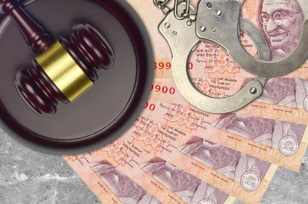 10 Indian rupees bills and judge hammer with police handcuffs on court desk. Concept of judicial trial or bribery. Tax avoidance or tax evasion