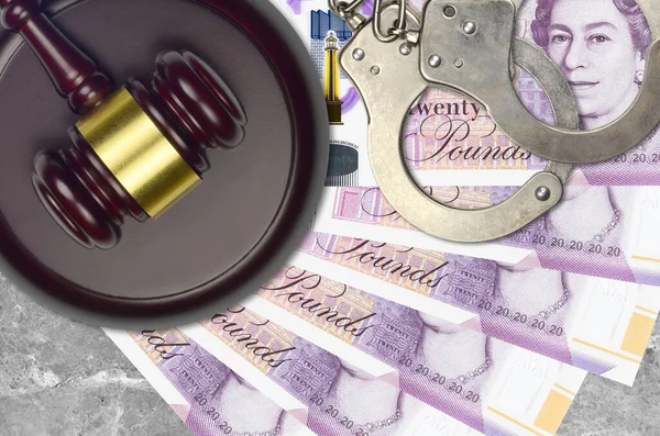 20 British pounds bills and judge hammer with police handcuffs on court desk. Concept of judicial trial or bribery. Tax avoidance or tax evasion