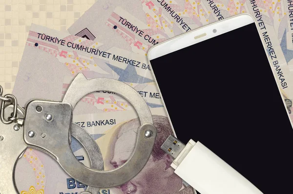 5 Turkish lira bills and smartphone with police handcuffs. Concept of hackers phishing attacks, illegal scam or online spyware soft distribution