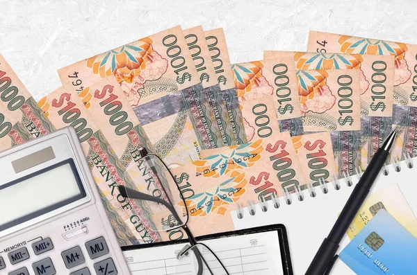 1000张圭亚那元钞票和带眼镜和笔的计算器纳税季节概念或投资解决方案 财务规划或会计文书 — 图库照片