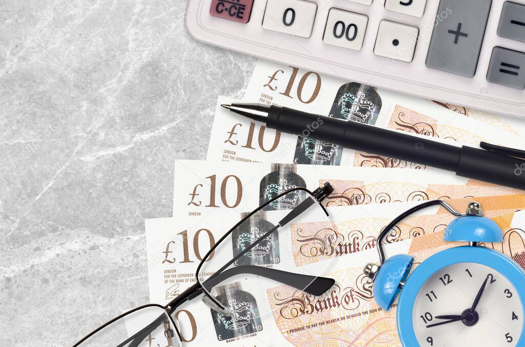 10 British pounds bills and calculator with glasses and pen. Business loan or tax payment season concept. Financial planning and time to pay taxes