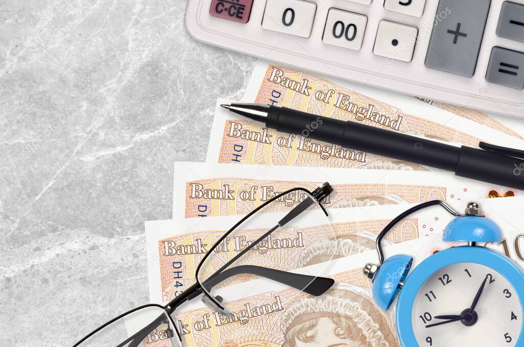 10 British pounds bills and calculator with glasses and pen. Business loan or tax payment season concept. Financial planning and time to pay taxes
