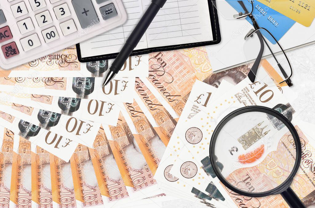 10 British pounds bills and calculator with glasses and pen. Tax payment season concept or investment solutions. Searching a job with high salary earnings