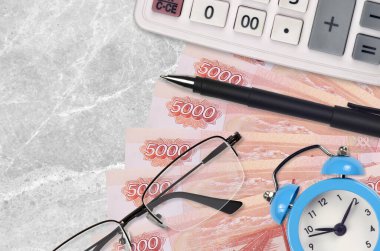 5000 Rus rublesi banknot, hesap makinesi, gözlük ve kalem. İş kredisi ya da vergi ödeme sezonu kavramı. Mali planlama ve vergi ödeme zamanı
