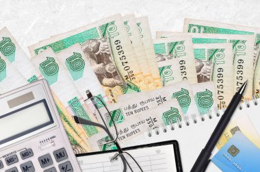 10 Sri Lanka rupisi fatura ve kalem ve gözlüklü hesap makinesi. Vergi ödeme sezonu kavramı veya yatırım çözümleri. Mali planlama ya da muhasebeci evrakları
