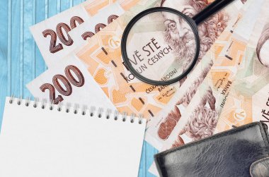 200 Çek korun banknotu ve siyah çantalı ve not defterli büyüteç. Sahte para konsepti. Sahte parayı tespit etmek için para banknotlarındaki farklılıkları araştır