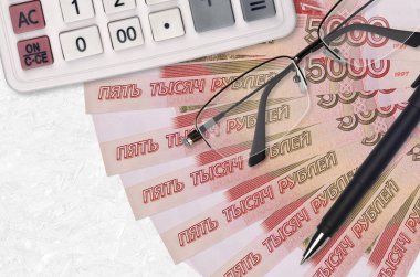 5000 rusya rublesi. Fan ve hesap makinesi. Gözlük ve kalemle. İş kredisi ya da vergi ödeme sezonu kavramı. Mali planlama