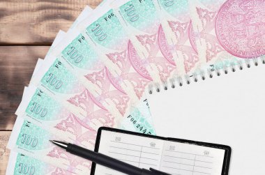 100 Çek korun fatura defteri ve siyah kalemli bir not defteri. Finansal planlama ve iş stratejisi kavramı. Muhasebe ve yatırım
