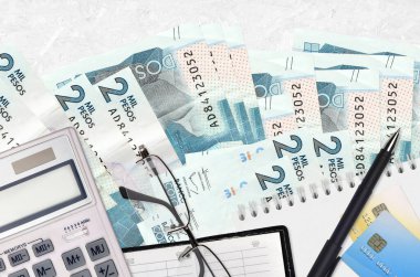 2 Kolombiya pezosu fatura ve kalem ve gözlüklü hesap makinesi. Vergi ödeme sezonu kavramı veya yatırım çözümleri. Mali planlama ya da muhasebeci evrakları