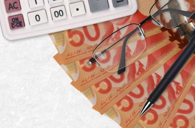 50 Kanada doları banknot fanı ve kalem ve gözlüklü hesap makinesi. İş kredisi ya da vergi ödeme sezonu kavramı. Mali planlama