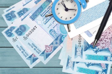 50 Sri Lanka rupisi ve içinde kalem ve zarflar olan çalar saat. Vergi sezonu konsepti, kredi veya kredi için ödeme tarihi. Posta servisini kullanarak finansal operasyonlar. Hızlı para transferi