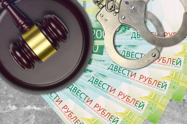 200 russian rubles bills and judge hammer with police handcuffs on court desk. Concept of judicial trial or bribery. Tax avoidance or tax evasion