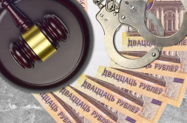 20 Belorussian rubles bills and judge hammer with police handcuffs on court desk. Concept of judicial trial or bribery. Tax avoidance or tax evasion