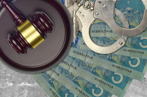 5 Canadian dollars bills and judge hammer with police handcuffs on court desk. Concept of judicial trial or bribery. Tax avoidance or tax evasion