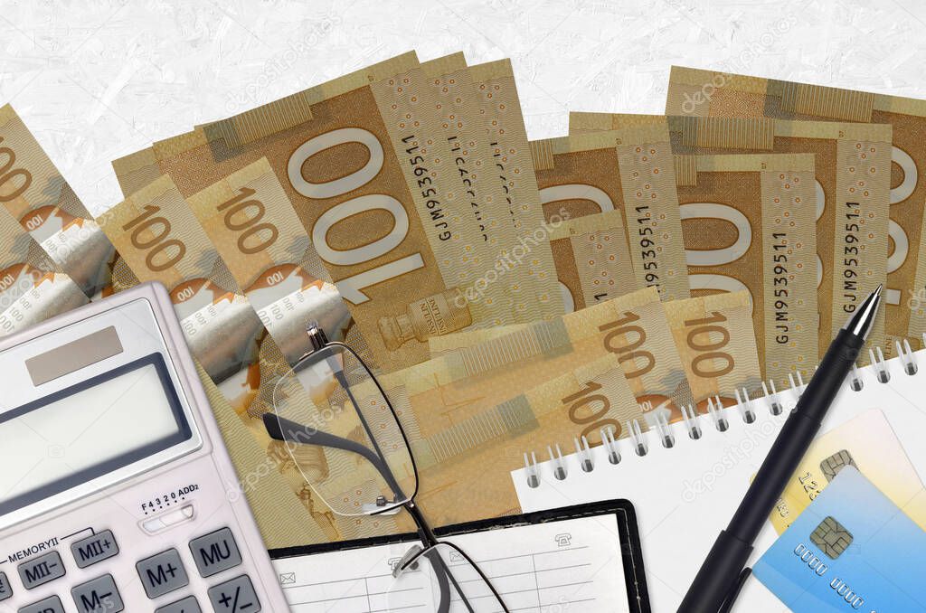 100 Canadian dollars bills and calculator with glasses and pen. Tax payment season concept or investment solutions. Financial planning or accountant paperwork