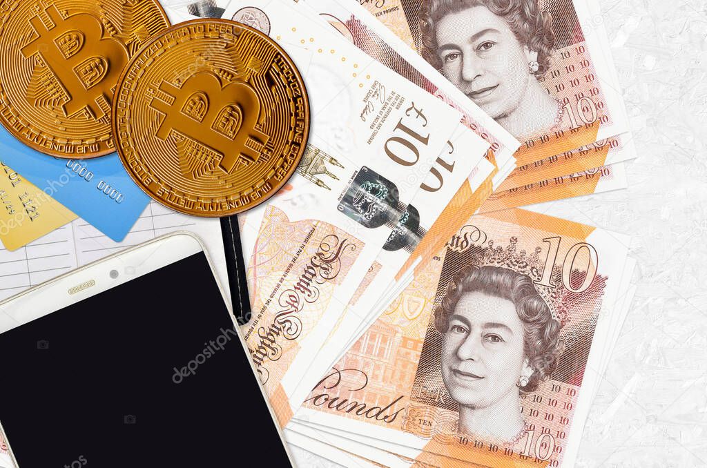 10 British pounds bills and golden bitcoins with smartphone and credit cards. Cryptocurrency investment concept. Crypto mining or trading transactions