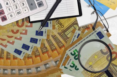 50 Euro 'luk banknotlar, hesap makinesi, gözlük ve kalem. Vergi ödeme sezonu kavramı veya yatırım çözümleri. Yüksek maaşlı bir iş arıyorum.