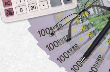100 Euro 'luk banknot fanı ve kalem ve gözlüklü hesap makinesi. İş kredisi ya da vergi ödeme sezonu kavramı. Mali planlama