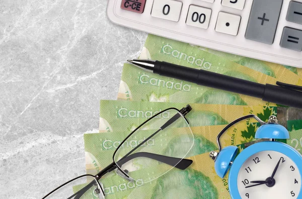 20 Canadian dollars bills and calculator with glasses and pen. Business loan or tax payment season concept. Financial planning and time to pay taxes