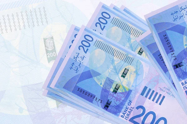 200 Israeli new shekels bills lies in stack on background of big semi-transparent banknote. Abstract presentation of national currency. Business concept