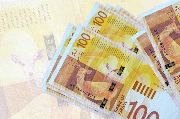 100 İsrailli yeni şekel banknotları büyük yarı şeffaf banknotların arka planında duruyor. Ulusal para biriminin soyut sunumu. İş konsepti