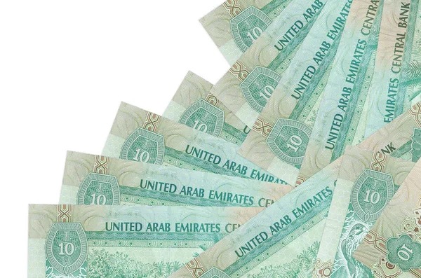 10 BAE Dirhams banknotu beyaza izole edilmiş farklı bir sırayla yatar. Yerel bankacılık ya da para kazanma konsepti. İş arkaplanı afişi