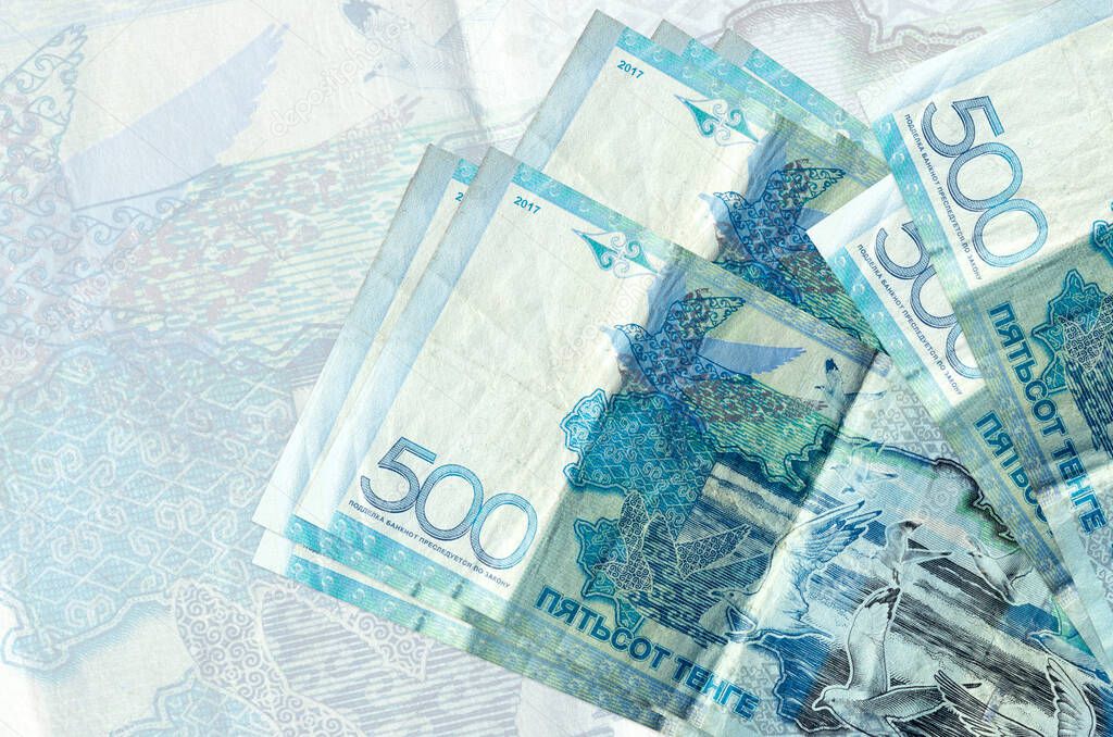 500 Kazakhstani tenge bills lies in stack on background of big semi-transparent banknote. Abstract presentation of national currency. Business concept