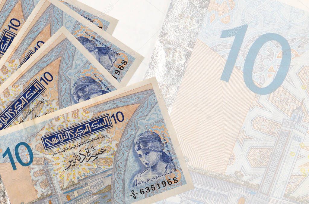10 Tunisian dinars bills lies in stack on background of big semi-transparent banknote. Abstract business background with copy space