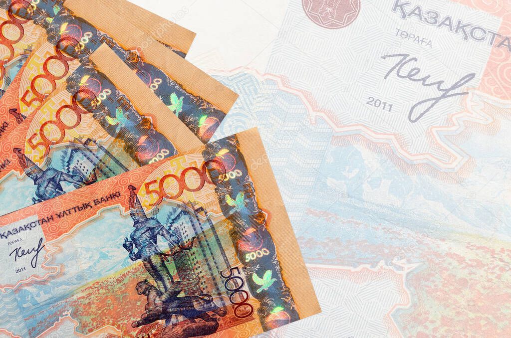 5000 Kazakhstani tenge bills lies in stack on background of big semi-transparent banknote. Abstract business background with copy space