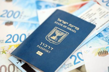 Israel New Shekels banknotları ve pasaportu. İsrail 'in mevcut para faturaları ve biyometrik geçiş kartı büyük miktarda masada yatıyor. İsrail 'de seyahat ve tatil kavramı