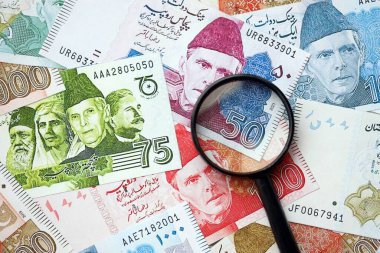 Pakistan banknotları ve büyüteç. Pakistan 'ın mevcut para ve büyüteç faturaları büyük miktarda masanın üzerinde duruyor. Pakistan 'da mali izleme ve vergilendirme kavramı