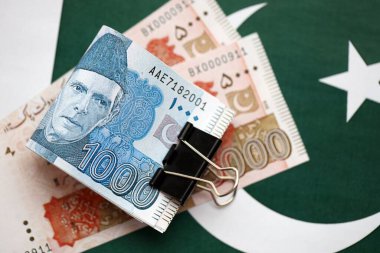 Pakistan bayrağı üzerinde Pakistan banknotları. Pakistan 'ın mevcut para faturaları büyük miktarlarda pankartta yatıyor. Pakistan 'da ekonomi ve ticaret kavramı