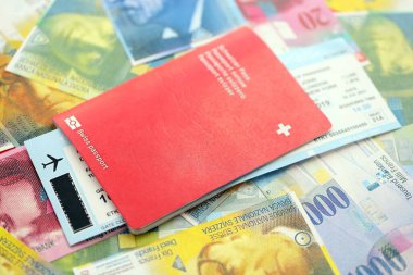 İsviçre frangı banknotları ve biletli pasaport. Mevcut banknotlar ve biyometrik geçiş kartları büyük miktarda masada yatıyor. İsviçre 'de seyahat ve tatil kavramı