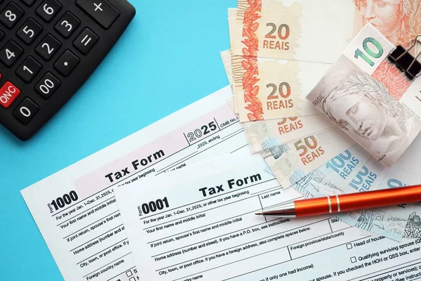 Brezilya banknotları, hesap makinesi ve vergi formlarıyla. Şu anki Brezilya gerçek para ve vergi borçları yakın plan. Brezilya 'da vergi ödeme ve muhasebe kavramı