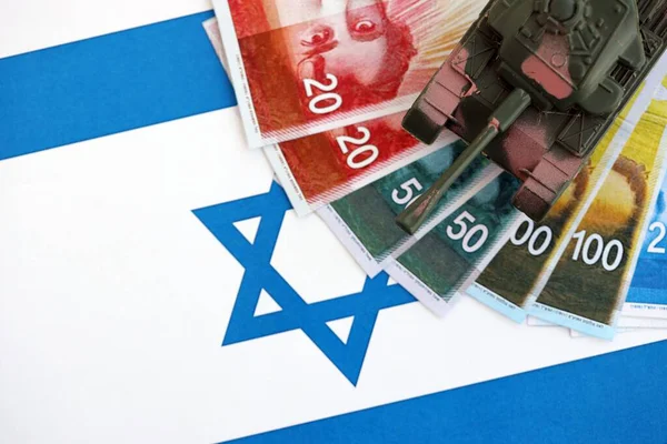 Israel New Shekels 'ın banknotları ve oyuncak tankları bayrağın üzerinde. İsrail 'in şu anki para ve tankı büyük oranda bayraklar üzerinde duruyor. İsrail 'de ordu fonları ve silah satışları kavramı